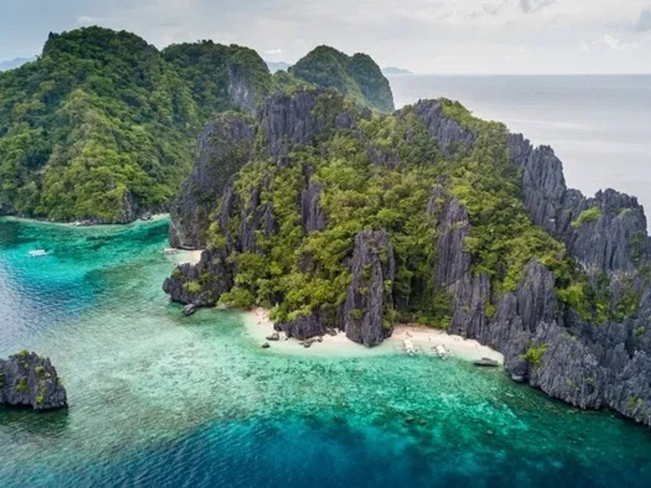 Isla tropical con formaciones rocosas, vegetación exuberante y aguas cristalinas.