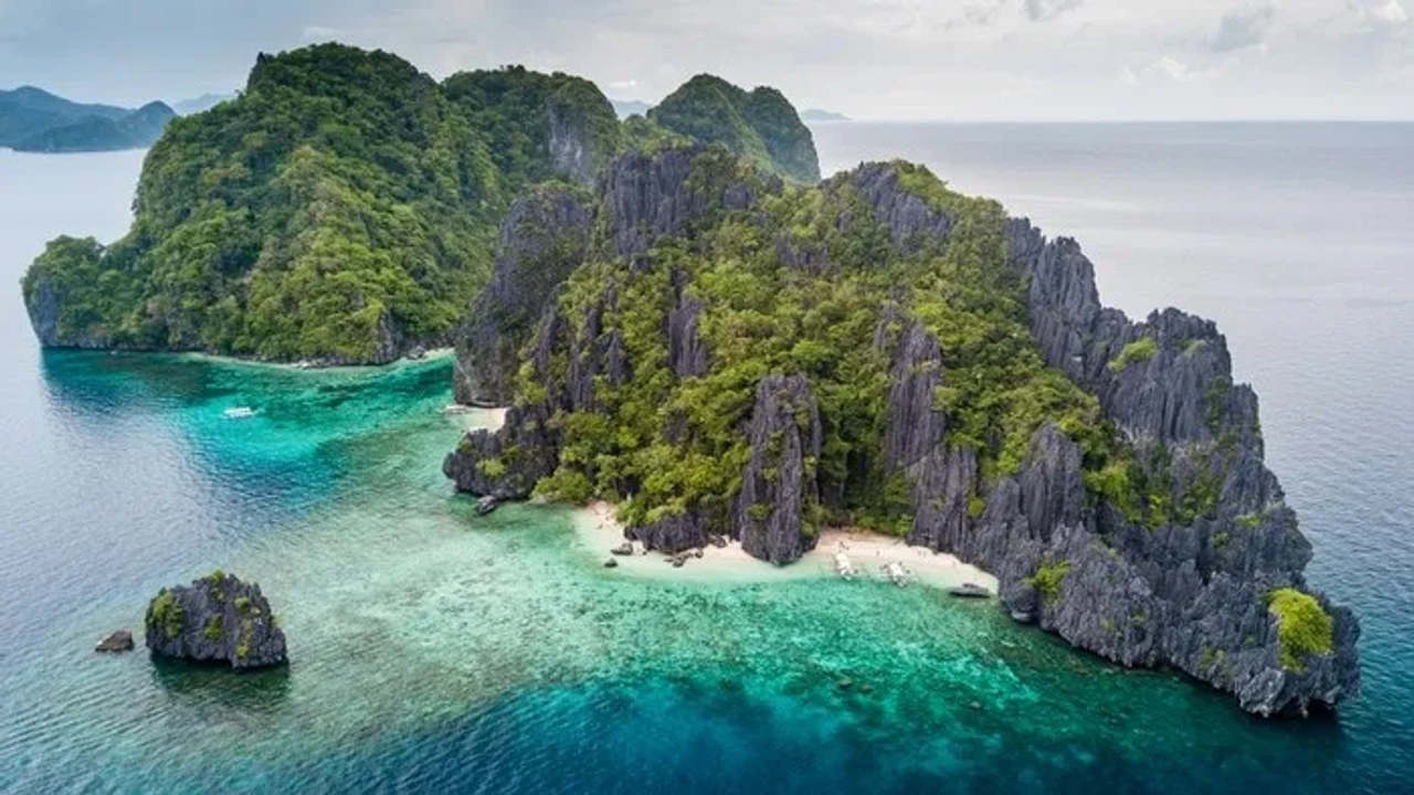 Isla tropical con formaciones rocosas, vegetación exuberante y aguas cristalinas.