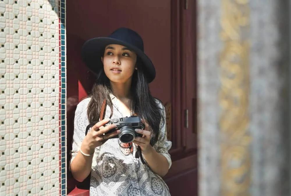 mulher com camara fotografica e chapeu preto