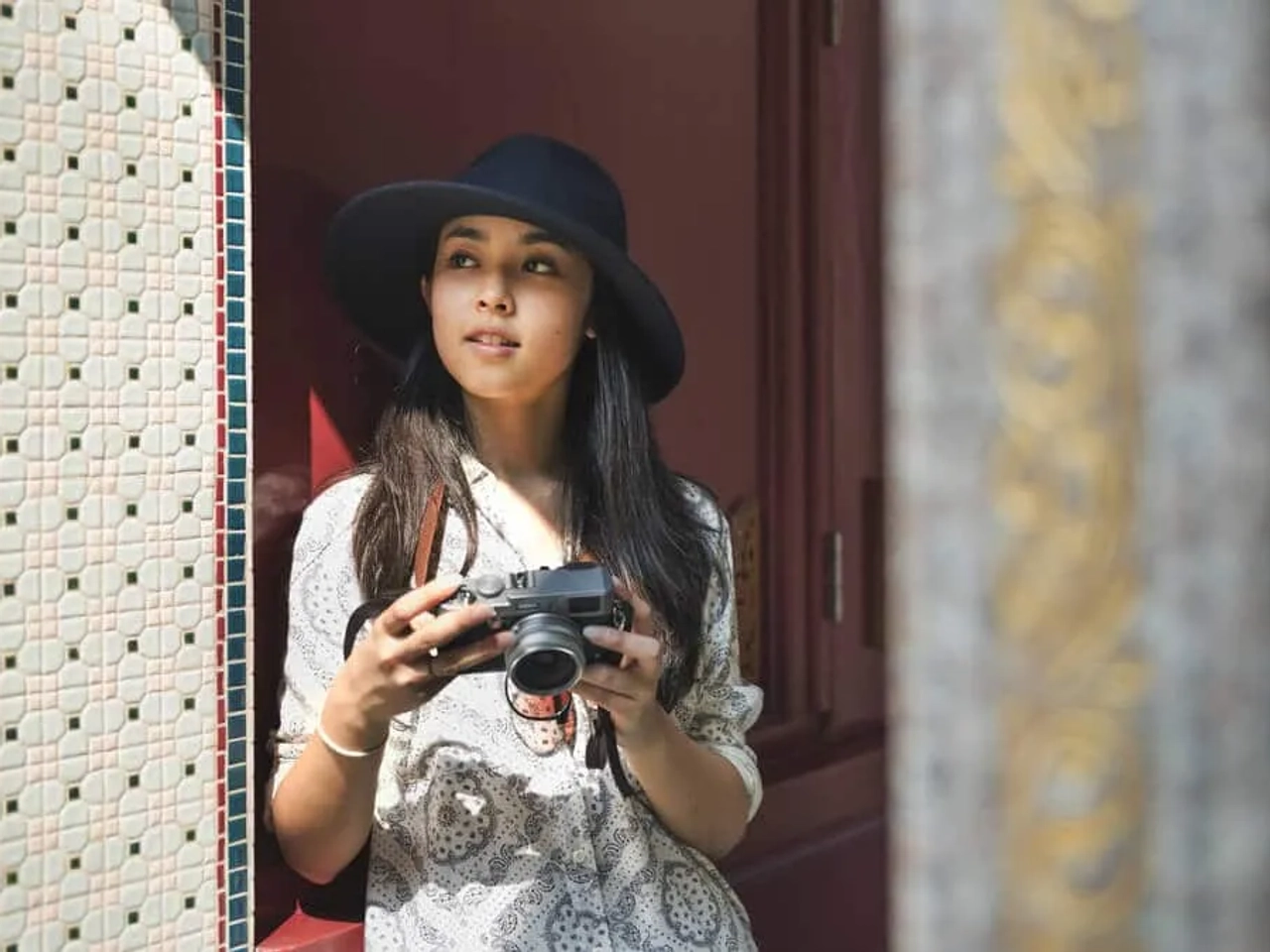 mulher com camara fotografica e chapeu preto