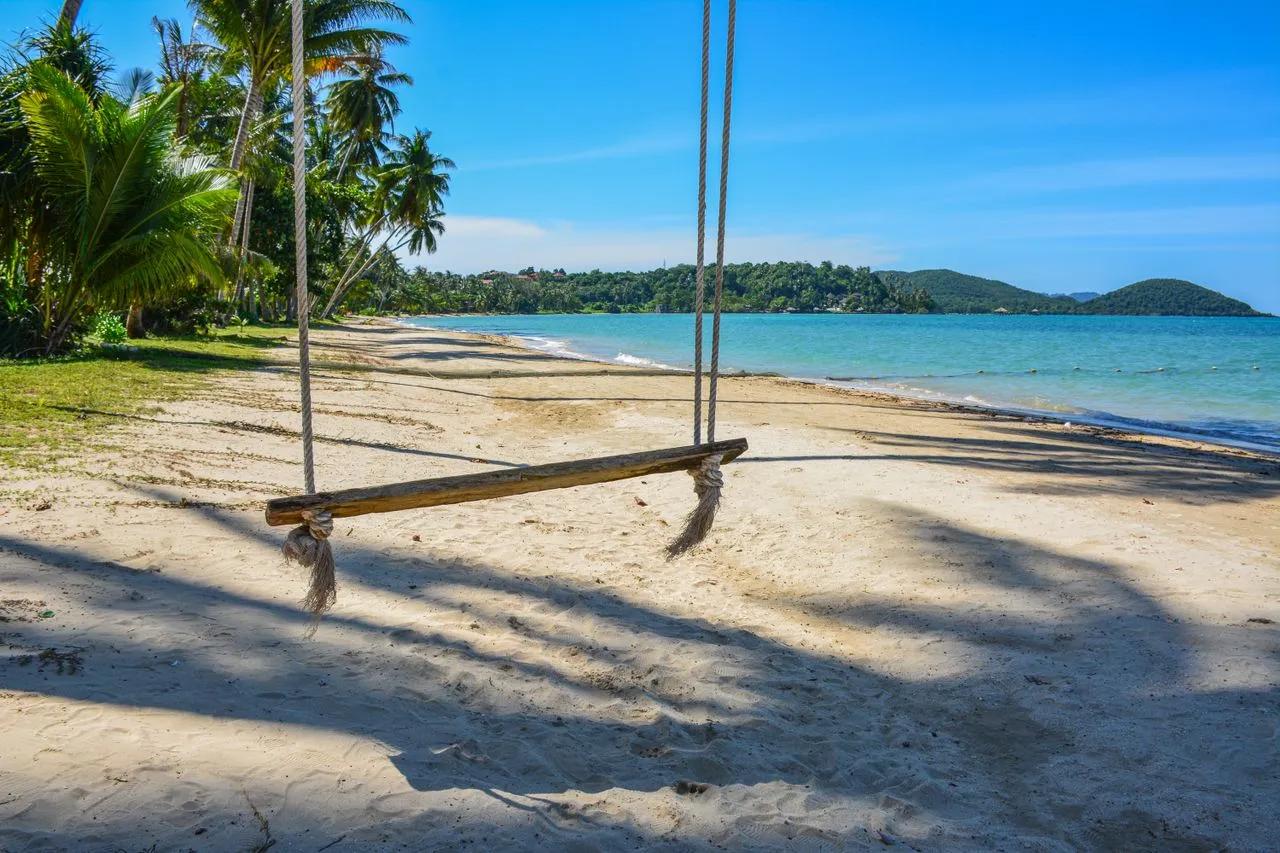 Spiaggia tropicale di Koh Samui in Thailandia con palme, altalena sulla sabbia e mare turchese.