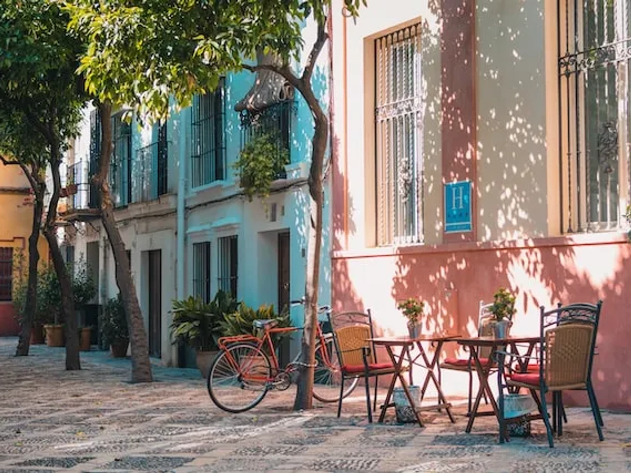 chairs around a table and a bike on a street of spain