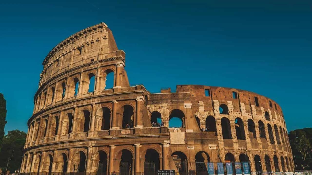 Coliseu de Roma, uma das sete maravilhas do mundo moderno, sob céu azul.