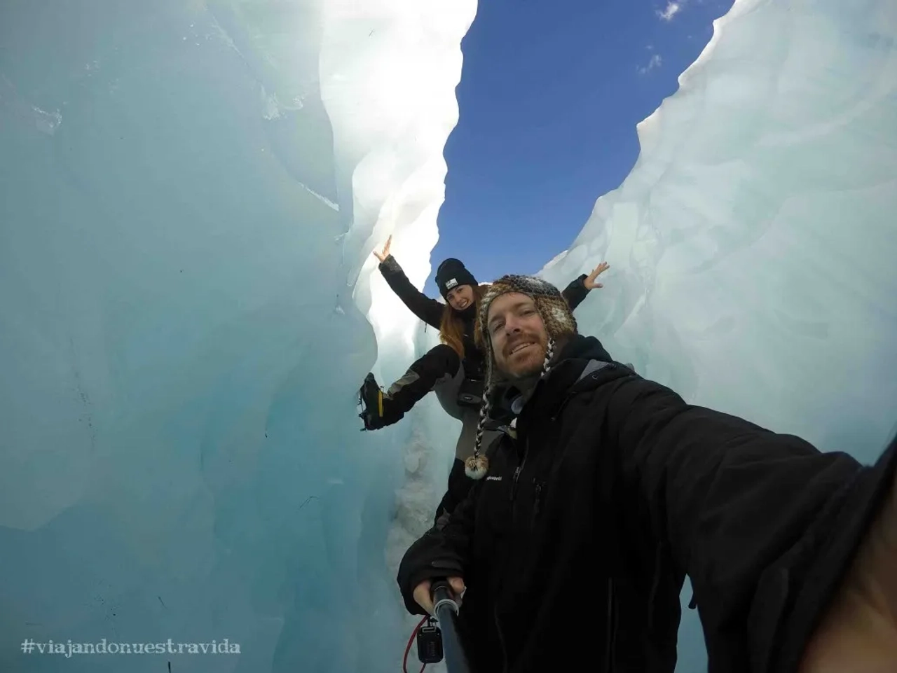 Pareja sonriente en un glaciar, disfrutando de la aventura al aire libre.