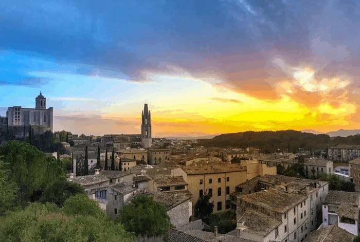 Vista panorámica de una ciudad con edificios históricos y un atardecer colorido.