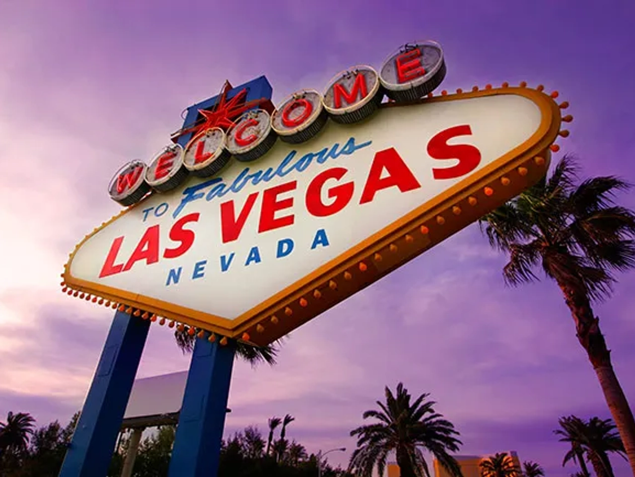 Cartel de bienvenida a Las Vegas, con palmeras y cielo púrpura.