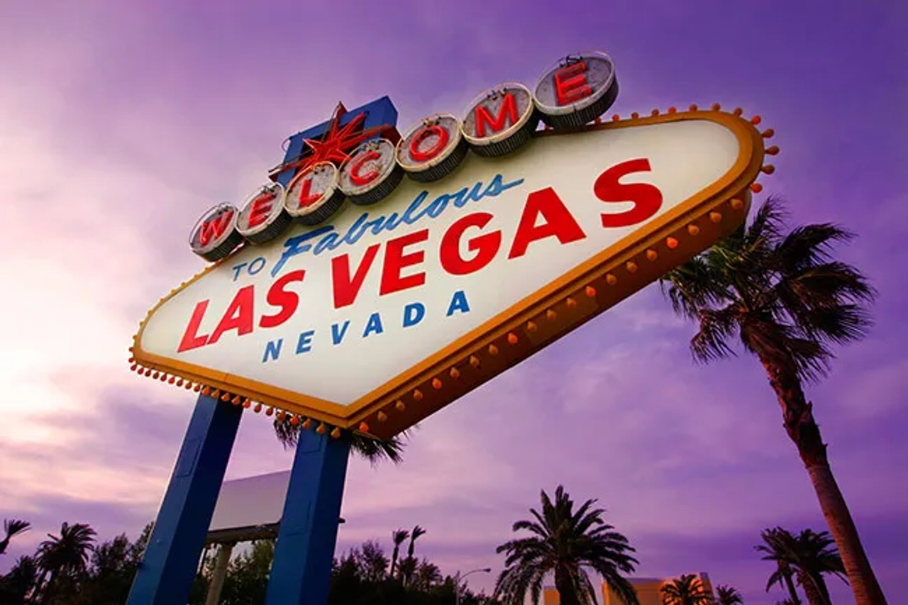 Cartel de bienvenida a Las Vegas, con palmeras y cielo púrpura.