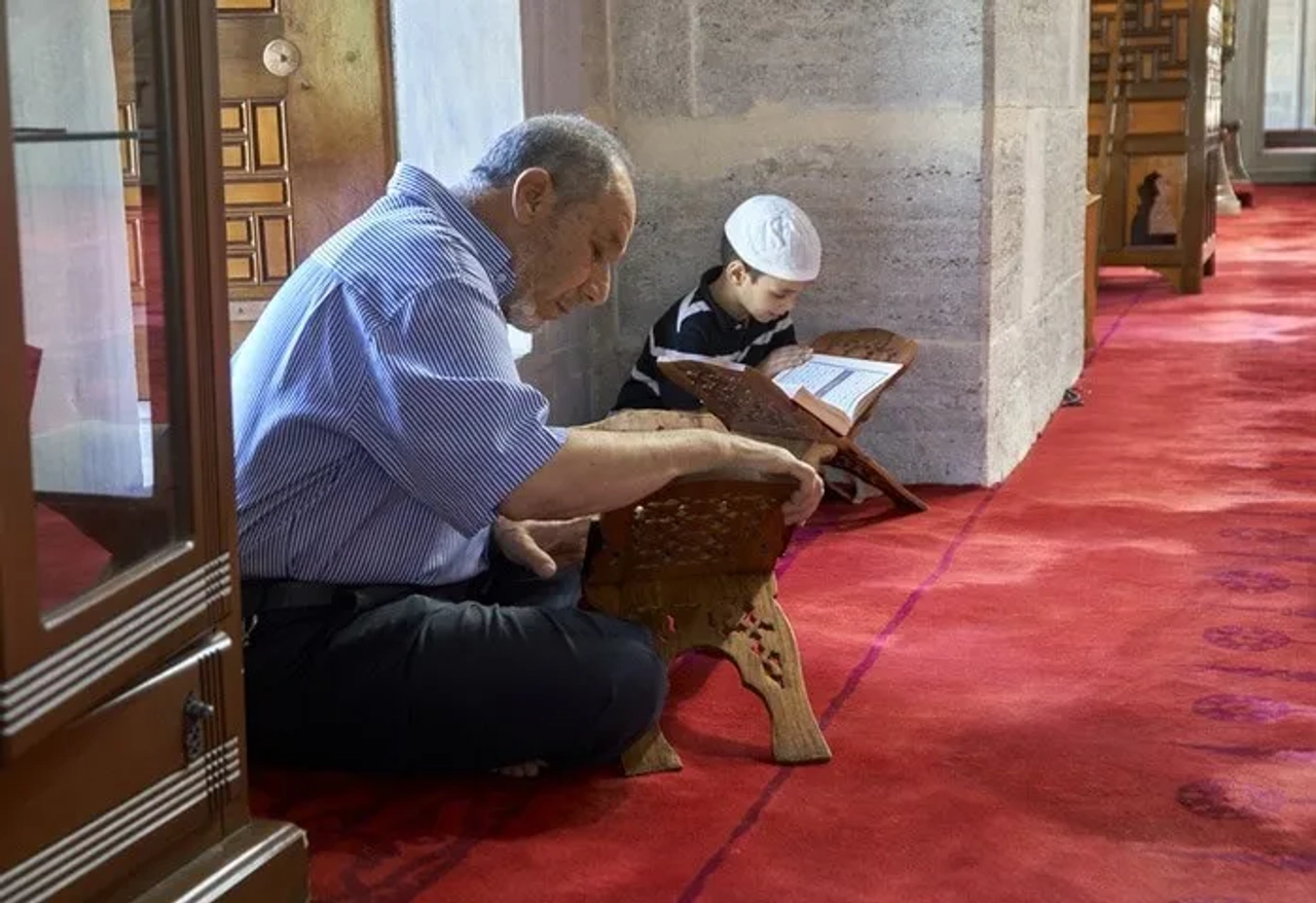 Un hombre y un niño leyendo el Corán en una mezquita.