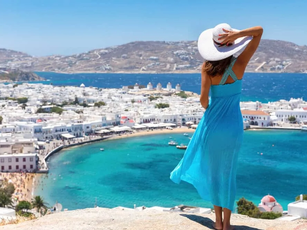 panoramica de mykonos e mulher de vestido azul