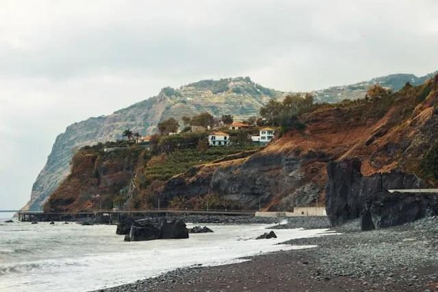 vista para uma praia de areia preta com casas na enseada no funchal na ilha da madeira
