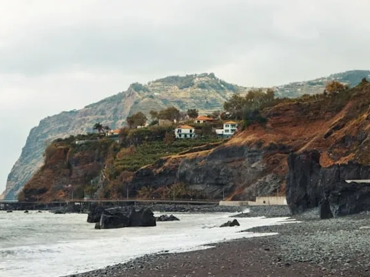 vista para uma praia de areia preta com casas na enseada no funchal na ilha da madeira