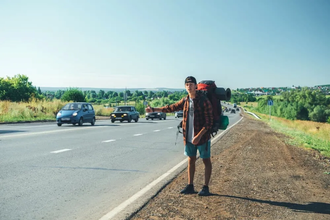 jovem com mochila de campismo pede boleia