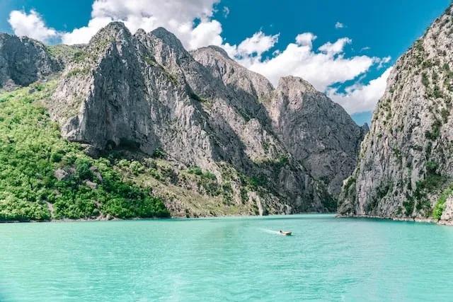 barco num rio azul turquesa no meio das montanhas na albania