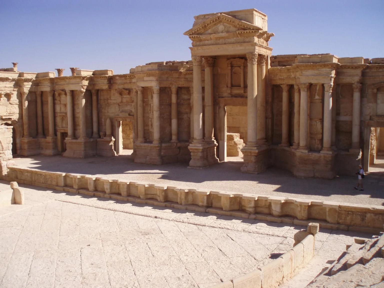 Ancient ruins with tall columns and a stone pathway under a clear blue sky.