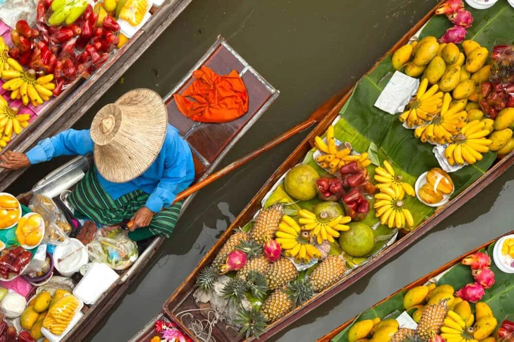mulher a vender fruta num barco no mercado flutuante
