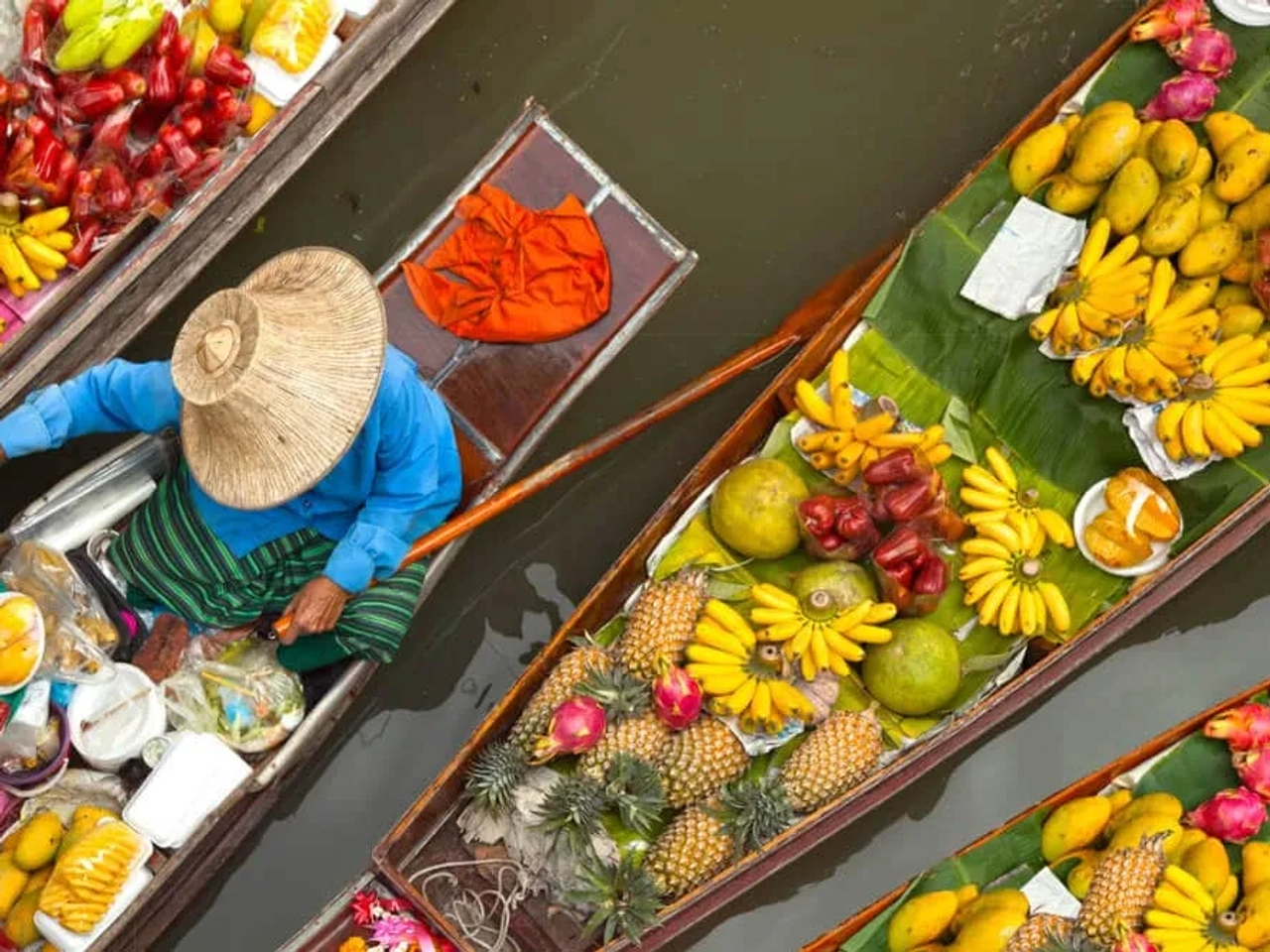mulher a vender fruta num barco no mercado flutuante