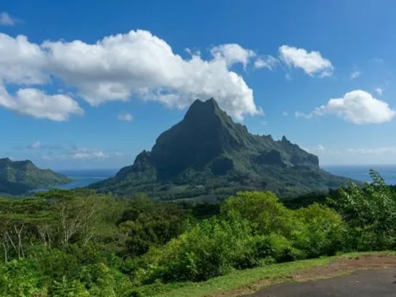 Montaña imponente rodeada de vegetación y mar en la Polinesia Francesa.