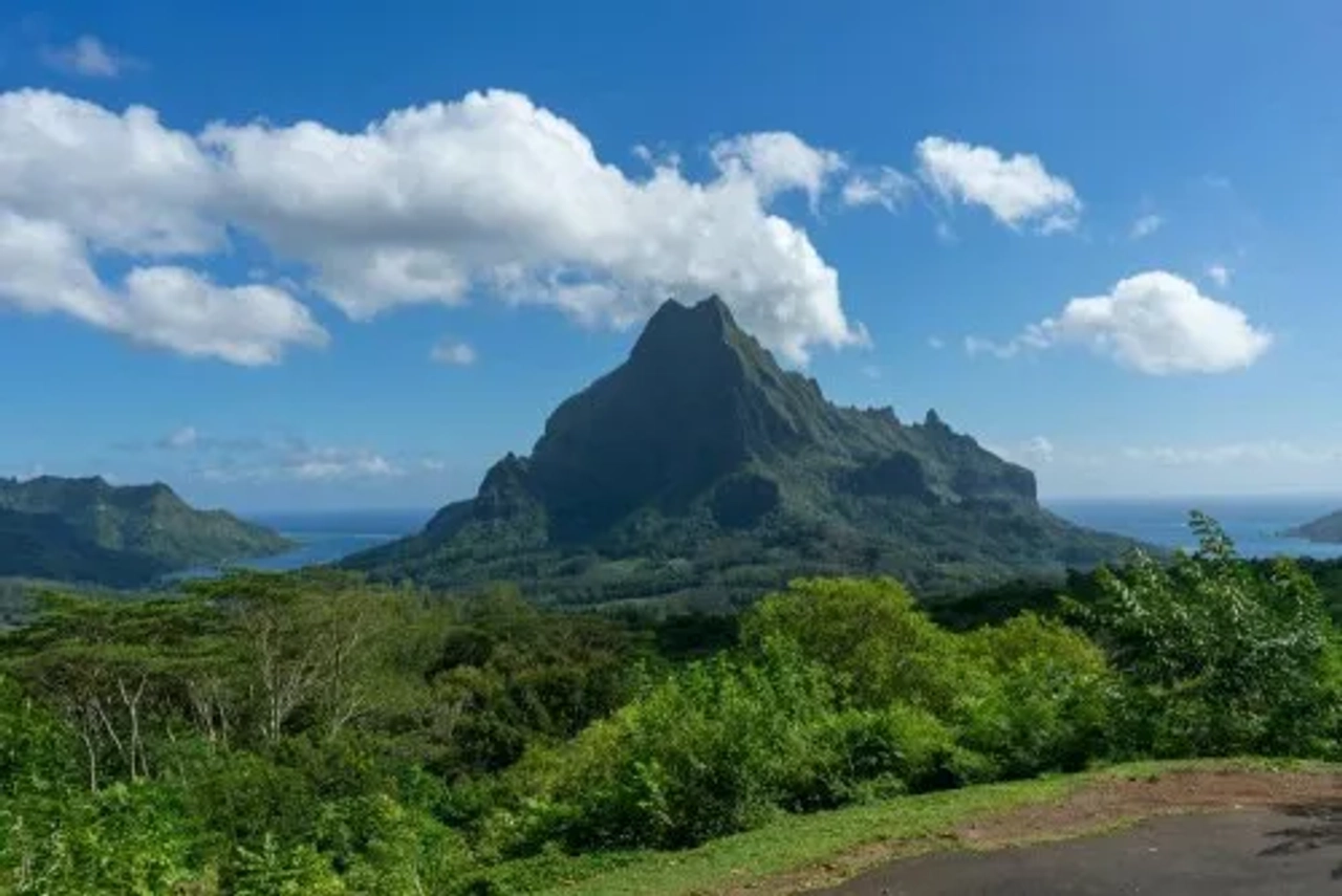 Montaña imponente rodeada de vegetación y mar en la Polinesia Francesa.