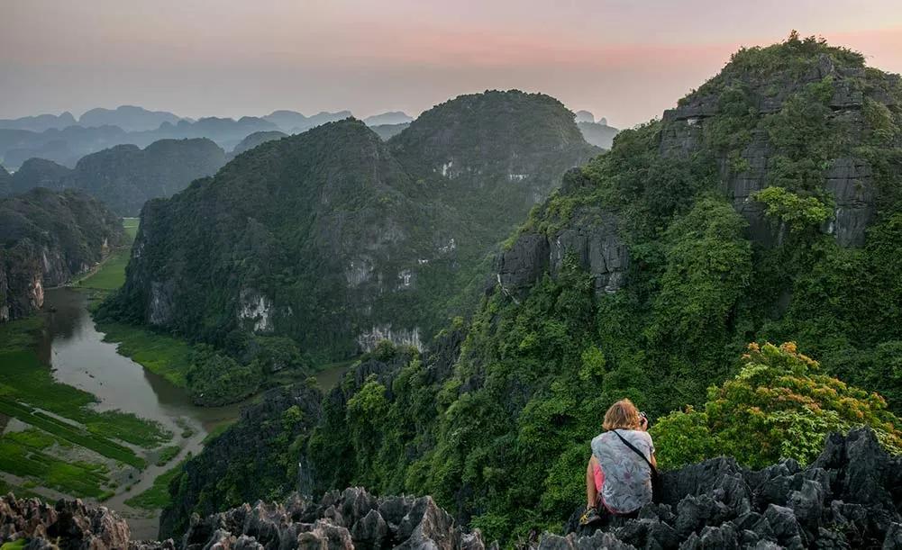 Persona contemplando un paisaje montañoso y verde en Vietnam al amanecer.