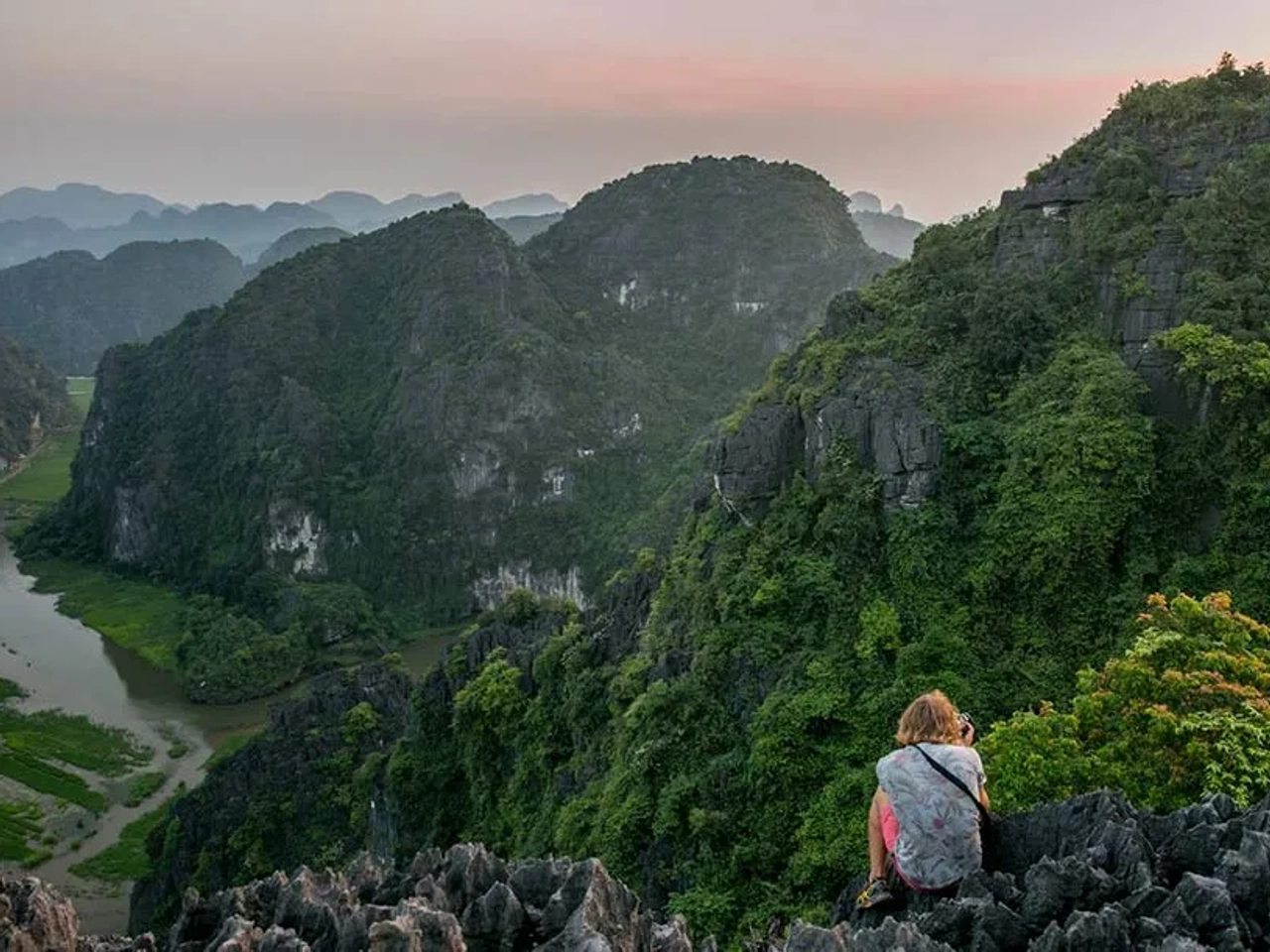 Persona contemplando un paisaje montañoso y verde en Vietnam al amanecer.