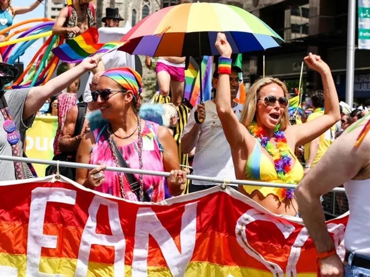 Celebración del Día del Orgullo Gay con personas vestidas coloridamente y banderas.