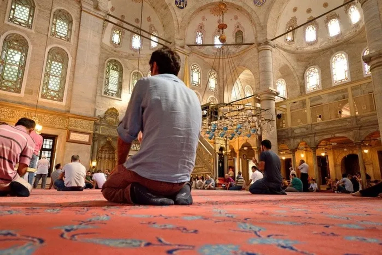 Interior de una mezquita en Estambul, con personas orando en el suelo.