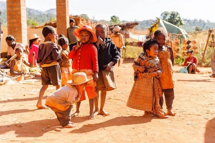 Niños jugando en un entorno rural de Madagascar, con vestimenta colorida y alegre.