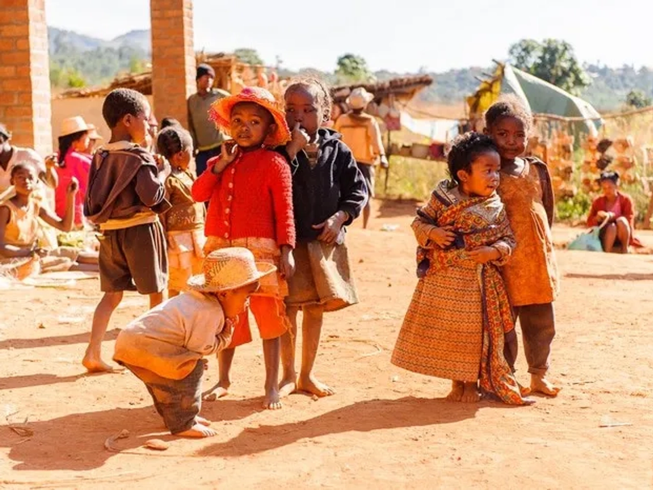 Niños jugando en un entorno rural de Madagascar, con vestimenta colorida y alegre.