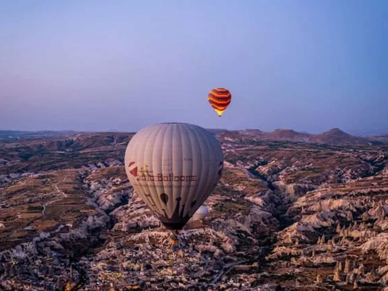 dois balões de ar quente a sobrevoar a capadócia com o céu cor de rosa e vistos de cima