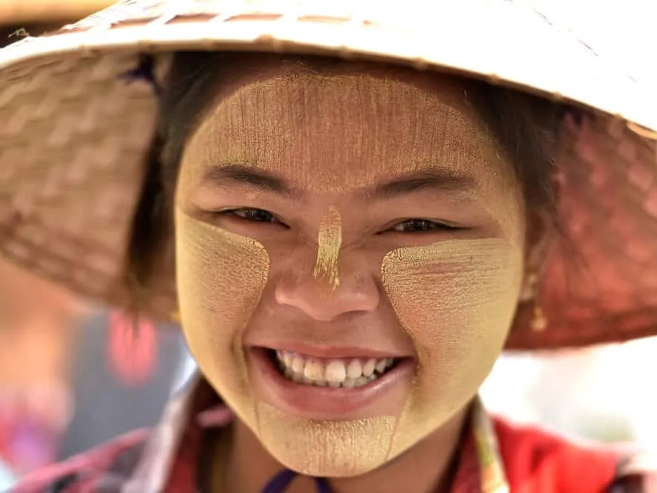 jovem de etnia burma sorri com chapeu de palha tipico