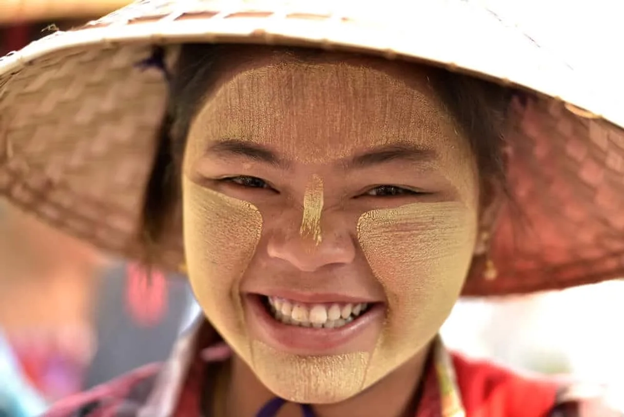 jovem de etnia burma sorri com chapeu de palha tipico