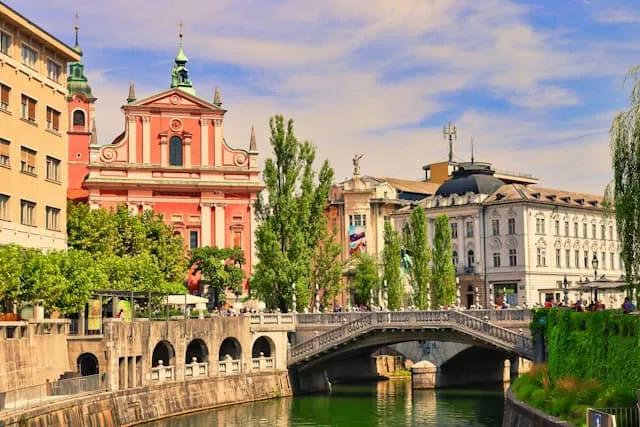 edificios coloridos junto a uma ponte com pessoas a passear em Ljubljana na eslovénia