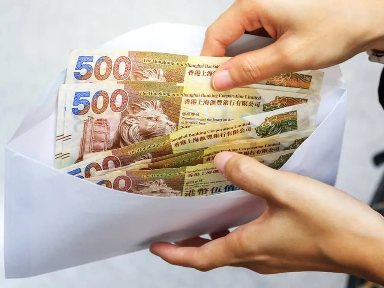 mãos a segurar envelope com quatro notas de 500 dolares de hong kong