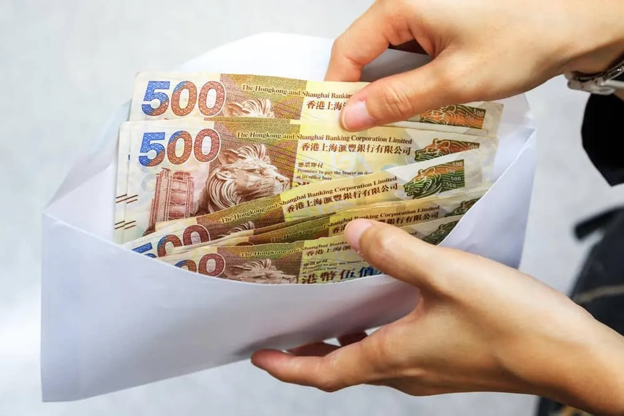 mãos a segurar envelope com quatro notas de 500 dolares de hong kong
