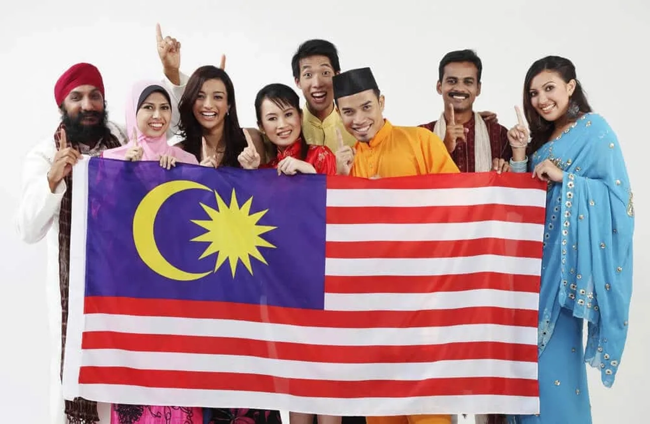 pessoas de varias descendencias seguram uma bandeira da malasia