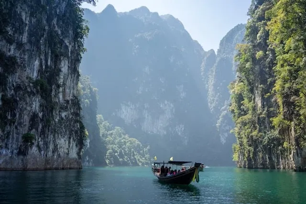Barca tradizionale sul lago Cheow Lan nel parco nazionale di Khao Sok, circondata da alte scogliere calcaree e giungla.
