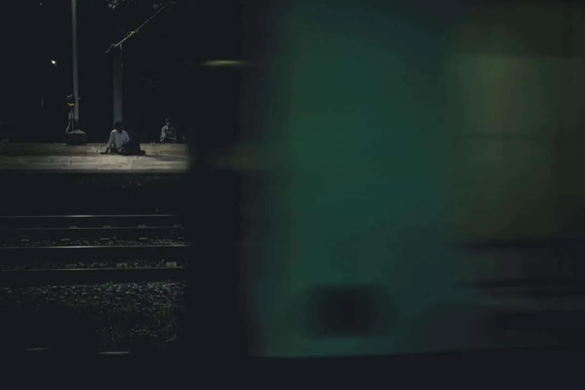 pessoa sentada à noite numa estaçao de comboios