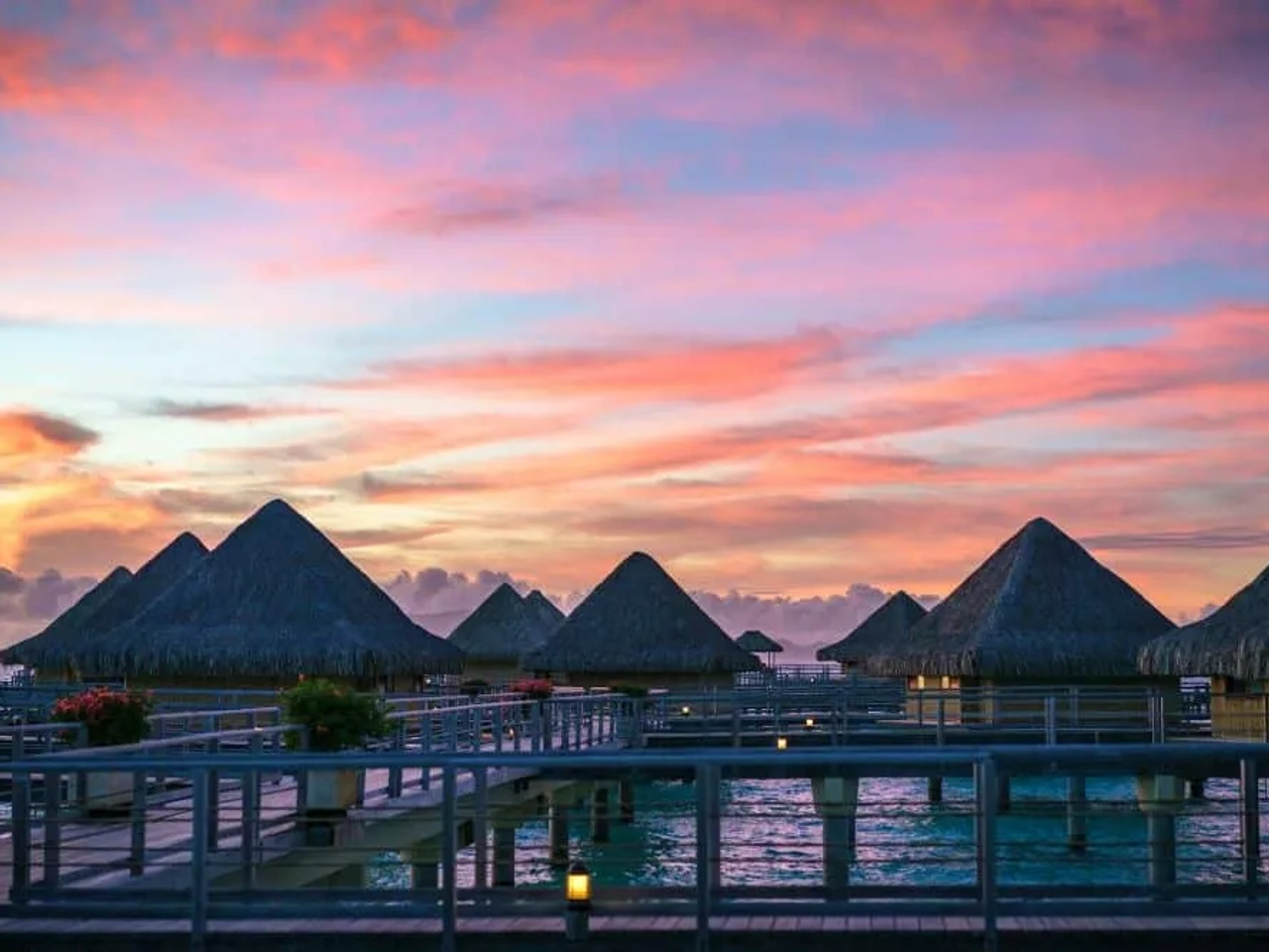 Atardecer sobre bungalows de palapa en la Polinesia Francesa.