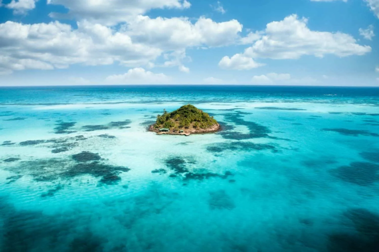 Ilha tropical cercada por águas cristalinas e céu azul. Ideal para viagens.