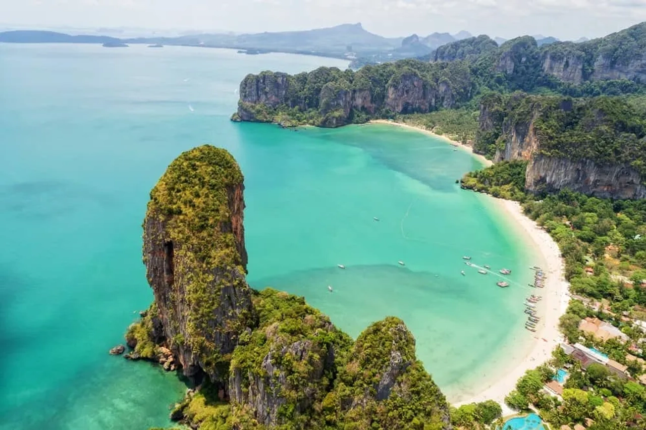 Vista aerea della spiaggia di Railay a Krabi, con mare turchese, scogliere calcaree e barche sulla costa.
