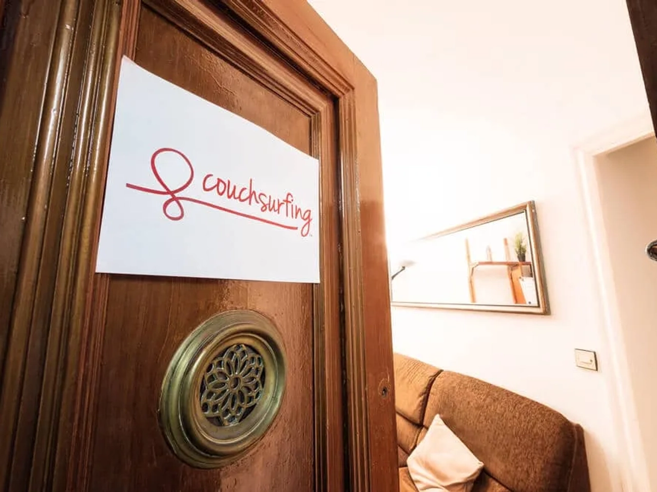 porta entreaberta com placa do couchsurfing