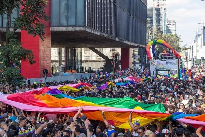 Multitud celebrando el Día del Orgullo Gay con una bandera arcoíris en la calle.