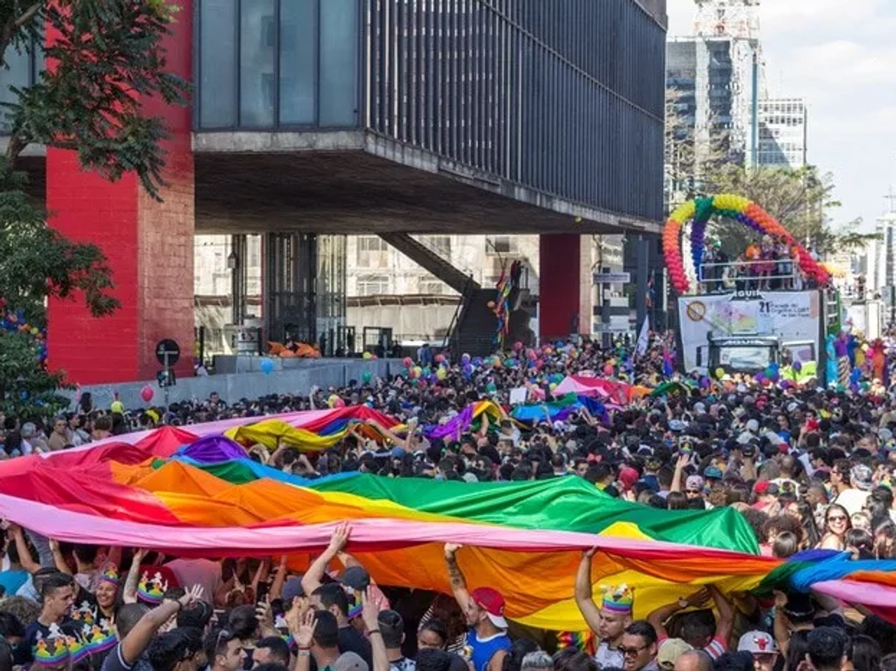 Multitud celebrando el Día del Orgullo Gay con una bandera arcoíris en la calle.