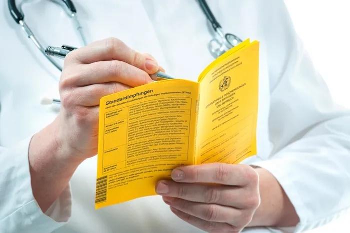 Médico revisando un pasaporte de vacunas para viajar al Sudeste Asiático.