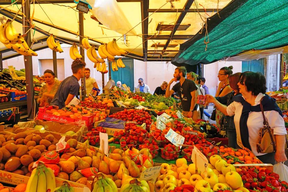 pessoas a comprar frutas numa banca do mercado