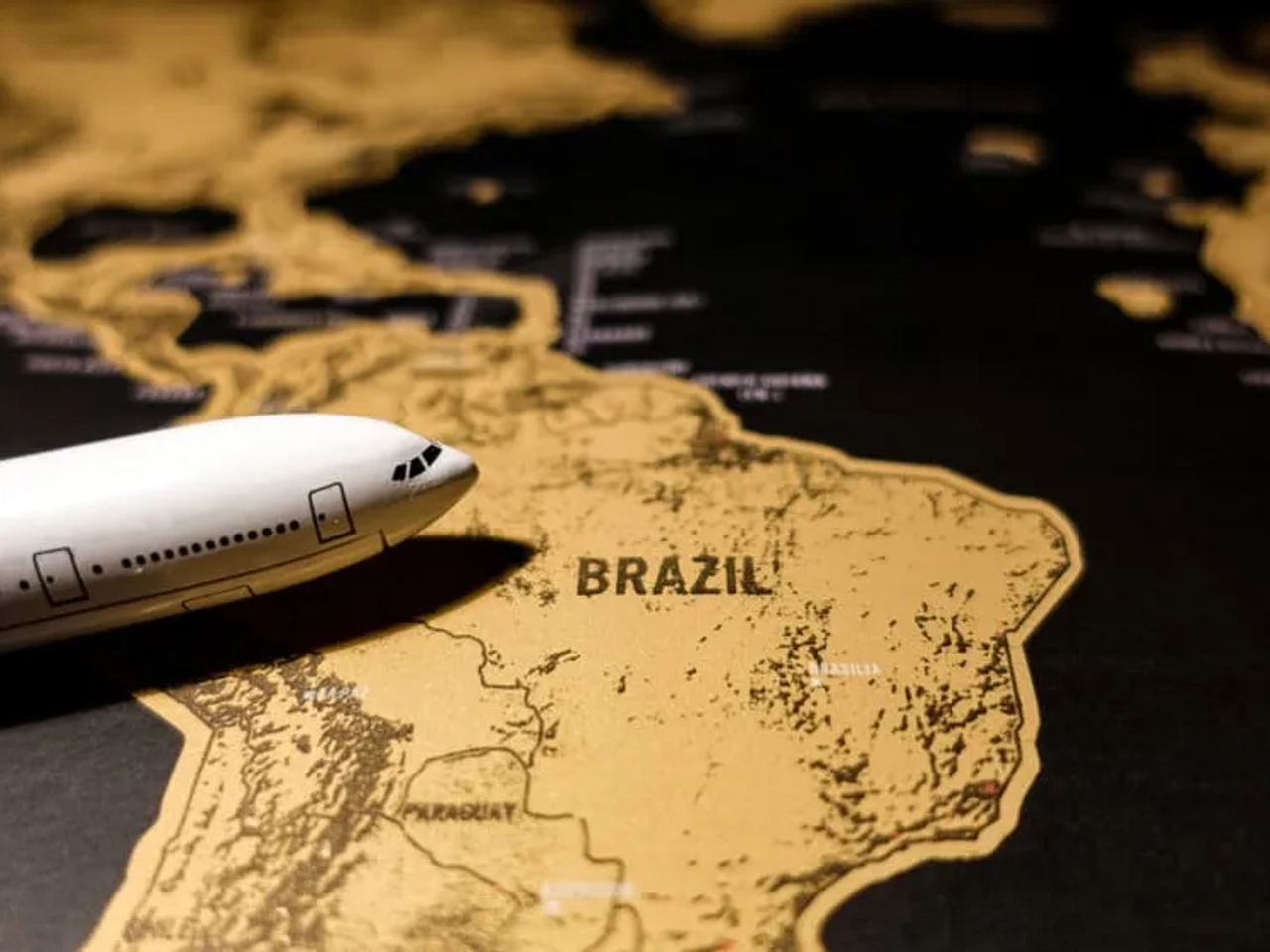 avião sobre mapa dourado do brasil
