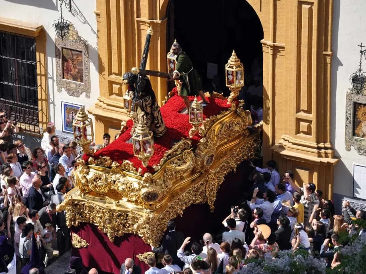 Procissão da Semana Santa com andor decorado e multidão assistindo.