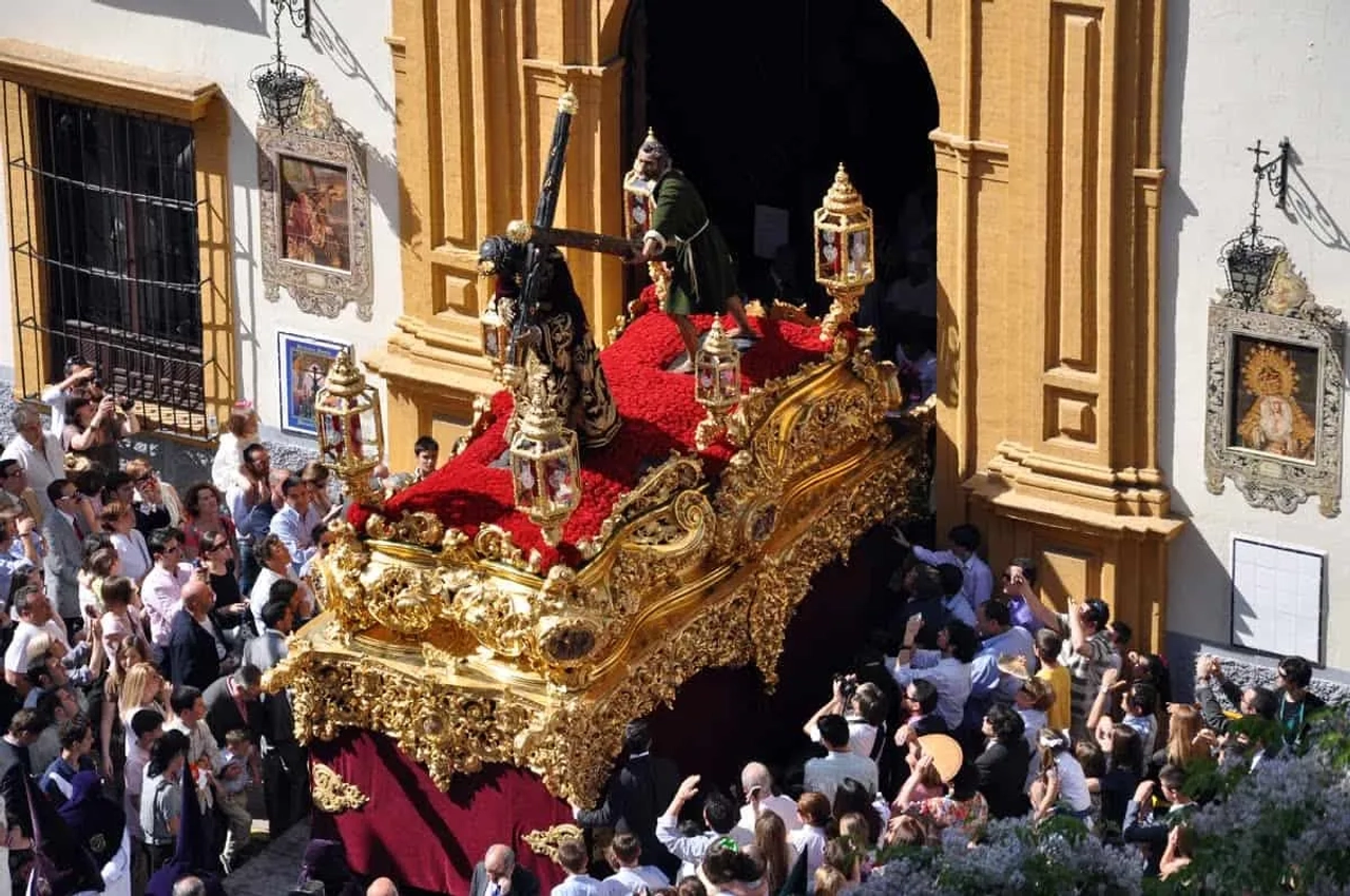 Procissão da Semana Santa com andor decorado e multidão assistindo.