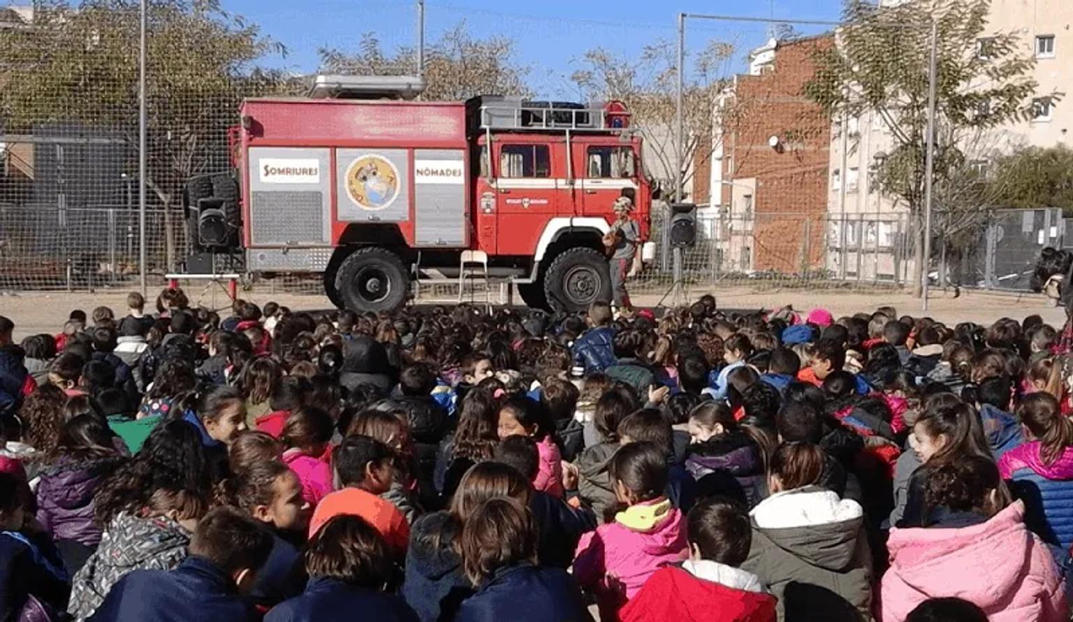 Niños sentados frente a un camión de bomberos durante una actividad educativa.