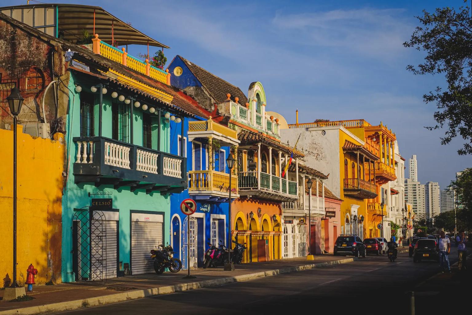 Colorful colonial buildings line a street in Cartagena, Colombia, under a clear blue sky.